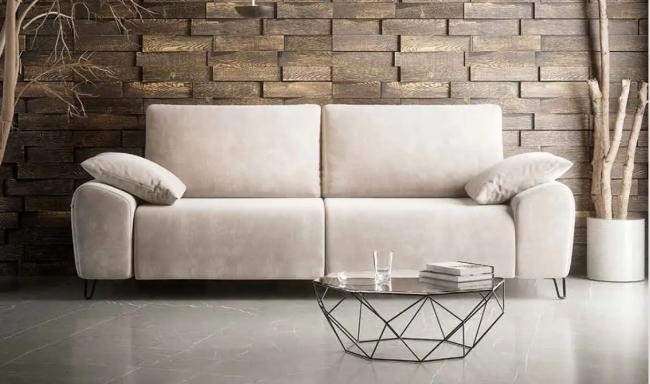Sofá de tela beige con cojines, frente a una pared de madera y mesa de centro de metal.